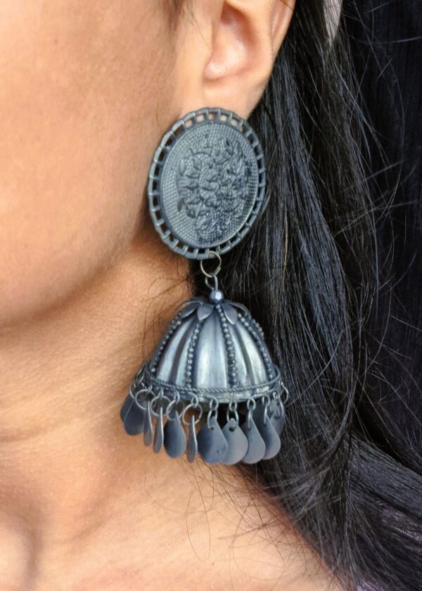 black oxidised jhumka earrings with intricate circular tops and dangling bell-shaped charms.